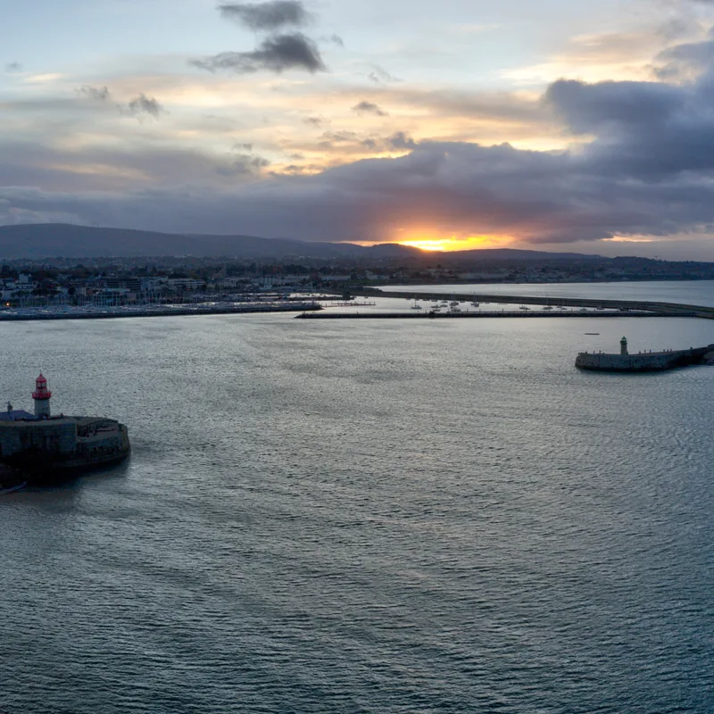 Dún Laoghaire harbour at sunset, light breaking through heavy cloud over the hills